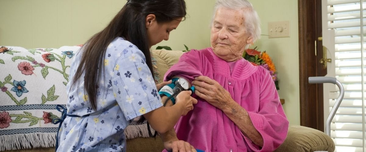 Family caregiver helping an older adult check blood pressure